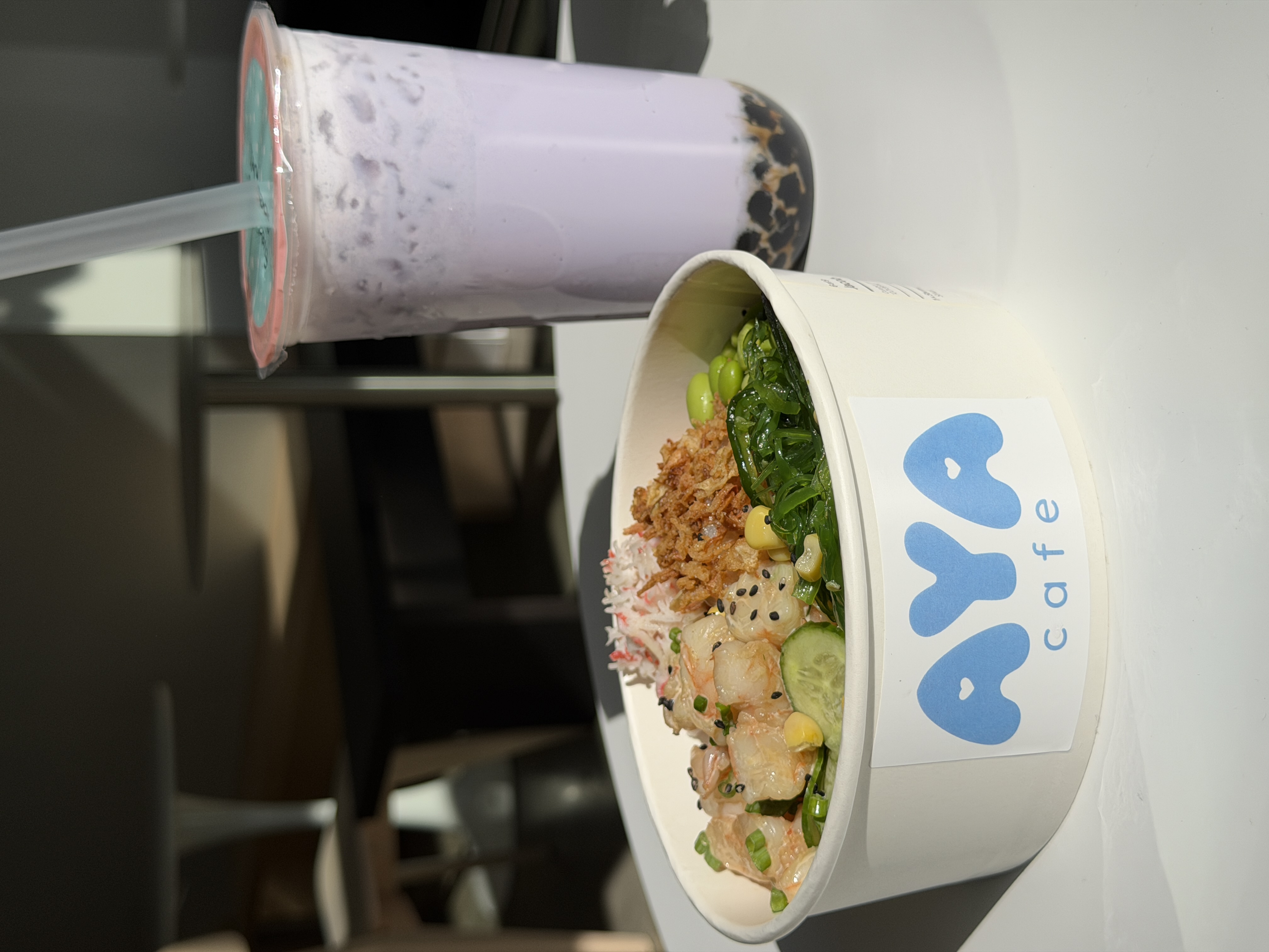 AYA poke bowl and taro boba on a sunlit café table