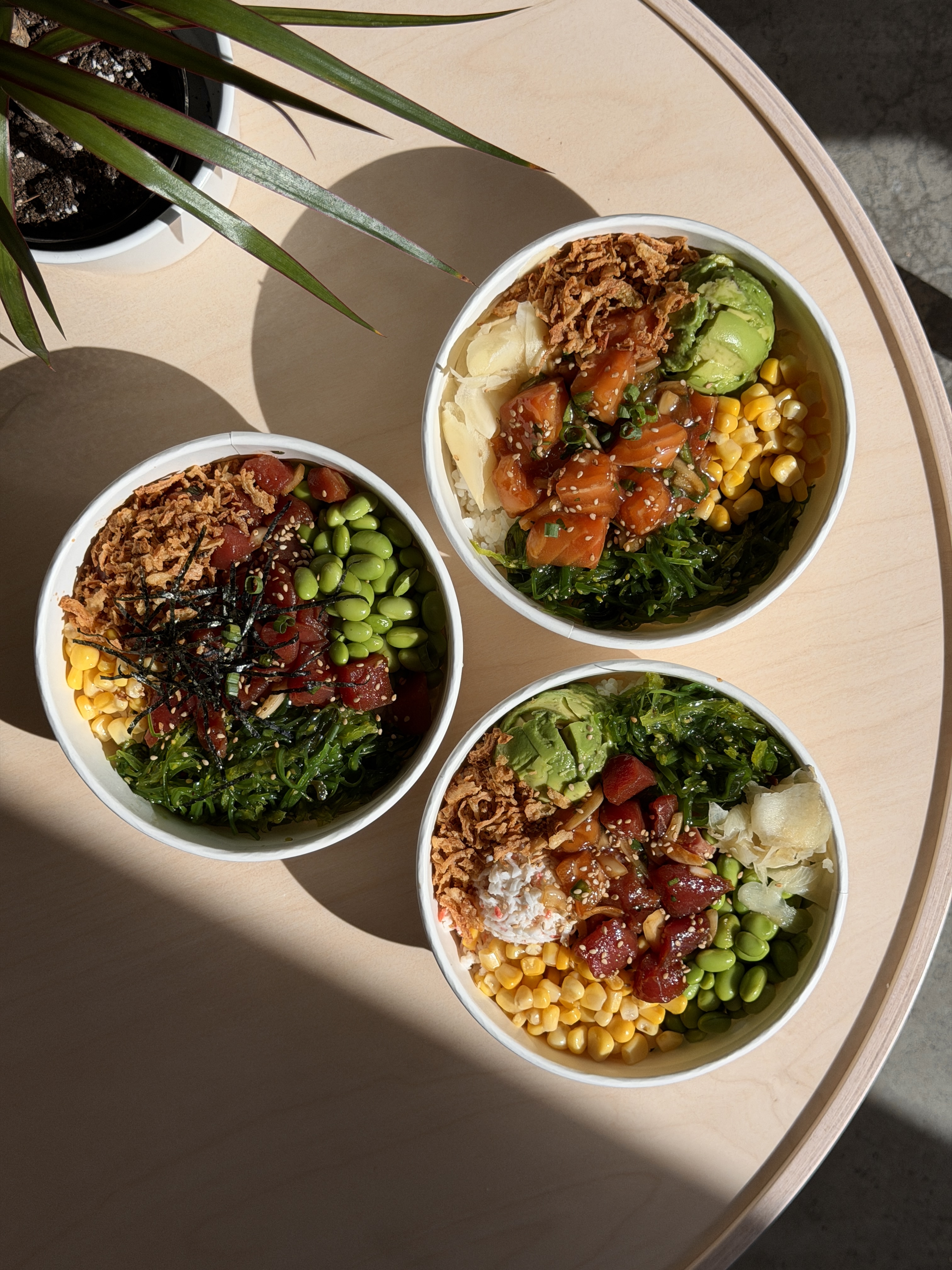 Three poke bowls with fish, vegetables and colorful toppings